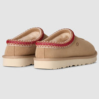 Pair of tan slippers with red trim on a light gray background