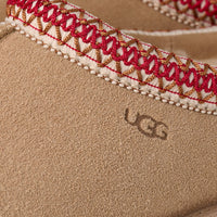 Close-up of a UGG shoe with embroidered strap on a beige background