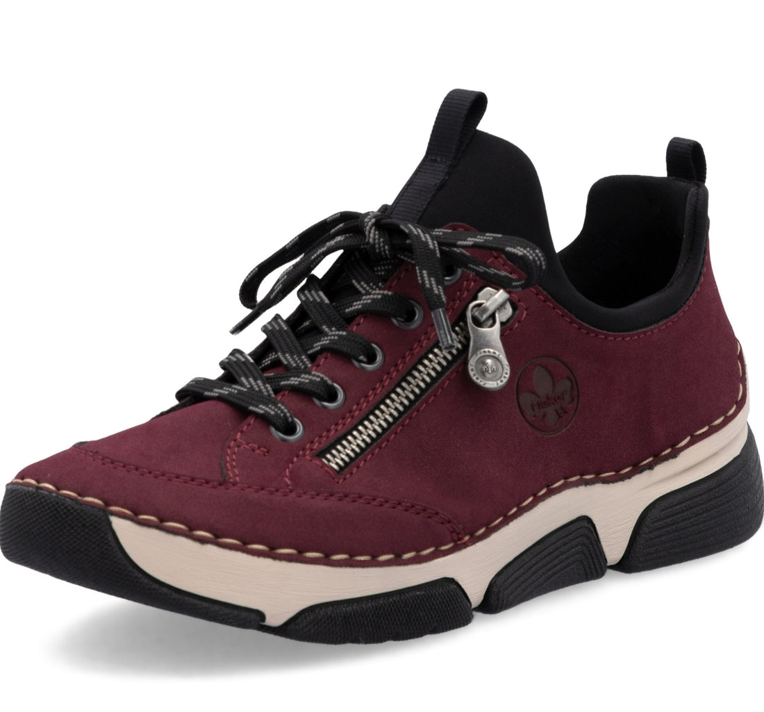 A low-top casual sneaker in burgundy suede with black laces, a black collar, a silver zipper, and a beige and black sole, shown on a white background.