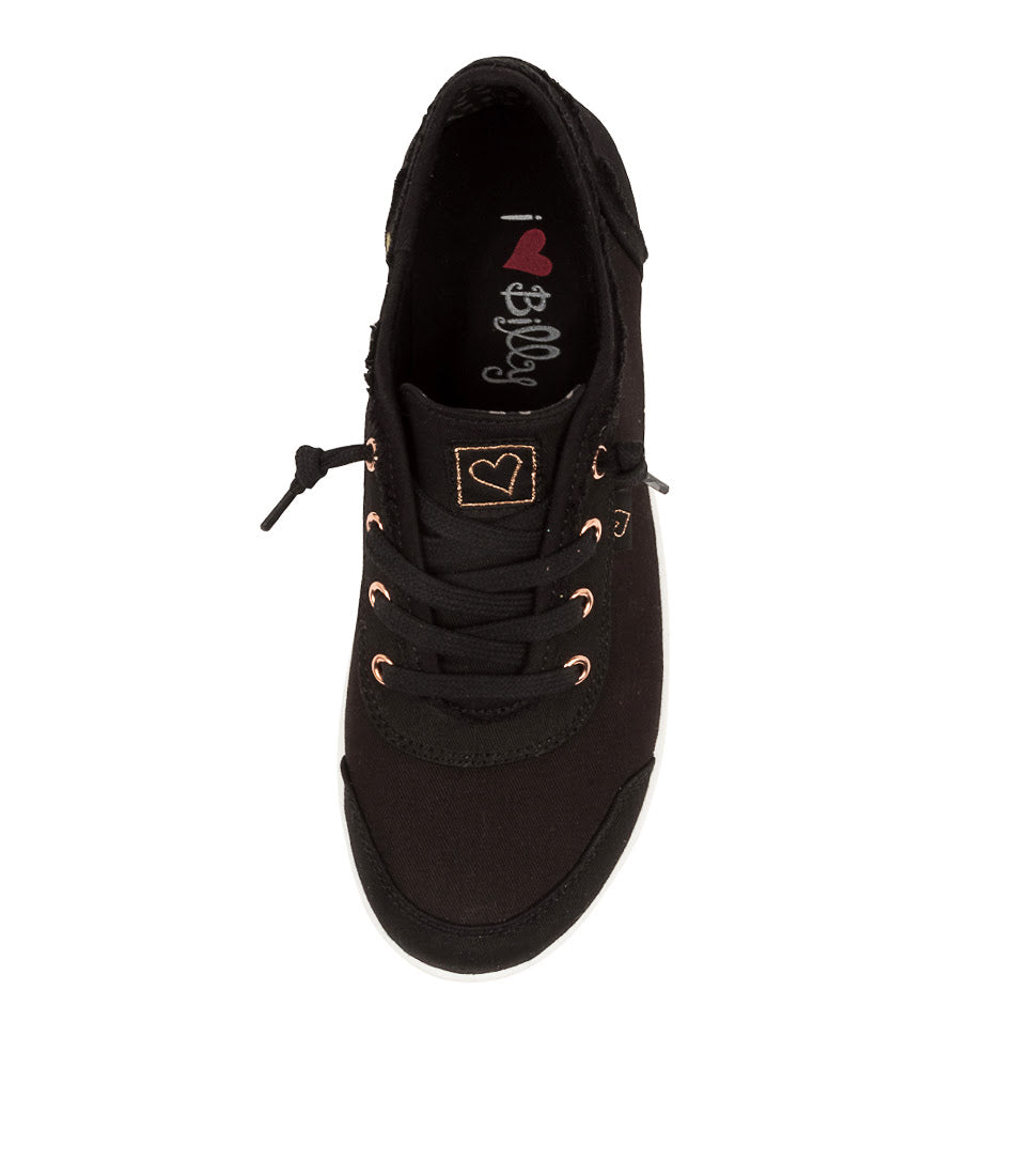 A black canvas low-top sneaker with black laces, rose gold eyelets, and a small square patch on the tongue featuring a heart and the brand name &