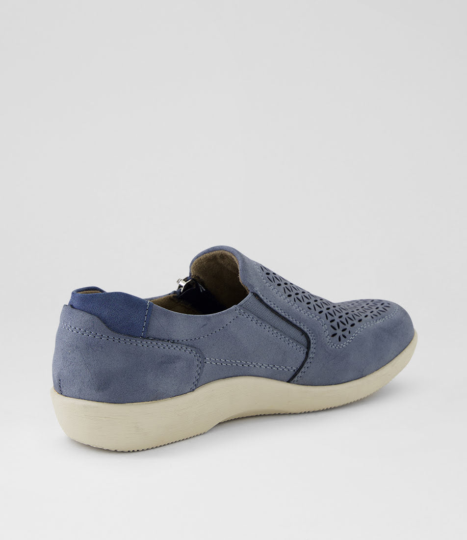 A single slip-on shoe in dusty blue suede with laser-cut geometric patterns on the toe, shown from a three-quarters rear angle against a light gray background.