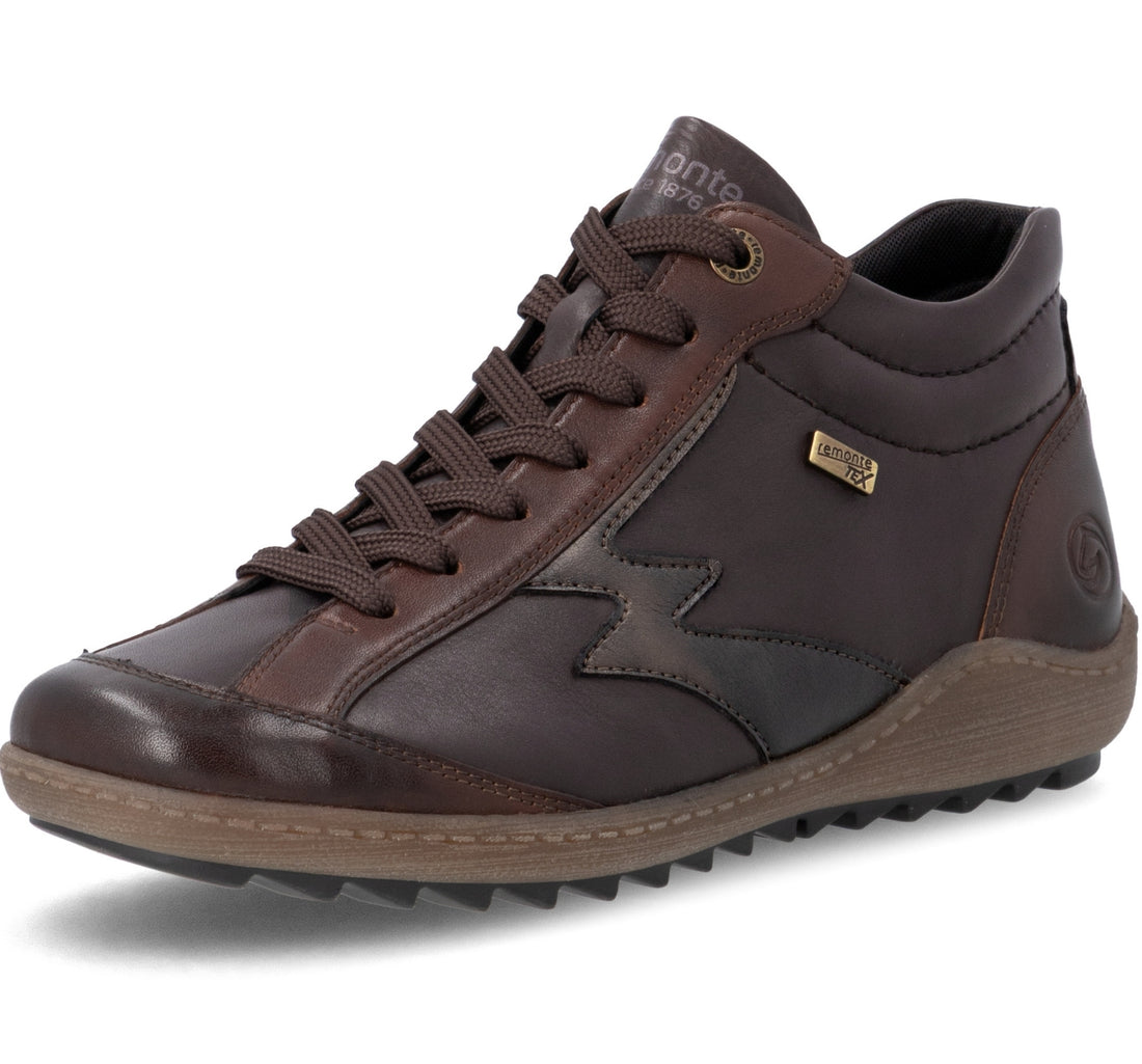 A dark brown leather mid-top shoe by Antje Petersen, featuring a lace-up front, a textured brown sole, and a small gold metal badge on the side.