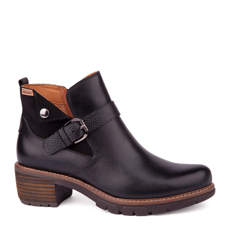 A black leather ankle boot with a side buckle strap, brown stacked block heel, and brown sole, shown from a side profile on a white background.